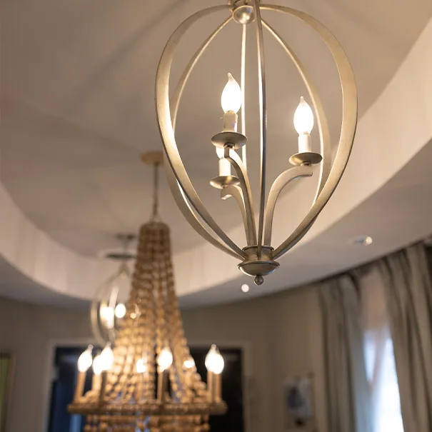 Silver open-cage pendant light above the curved reception ceiling