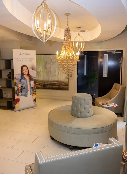 Waiting area with tiered chandeliers, lounge seating and a patient information display